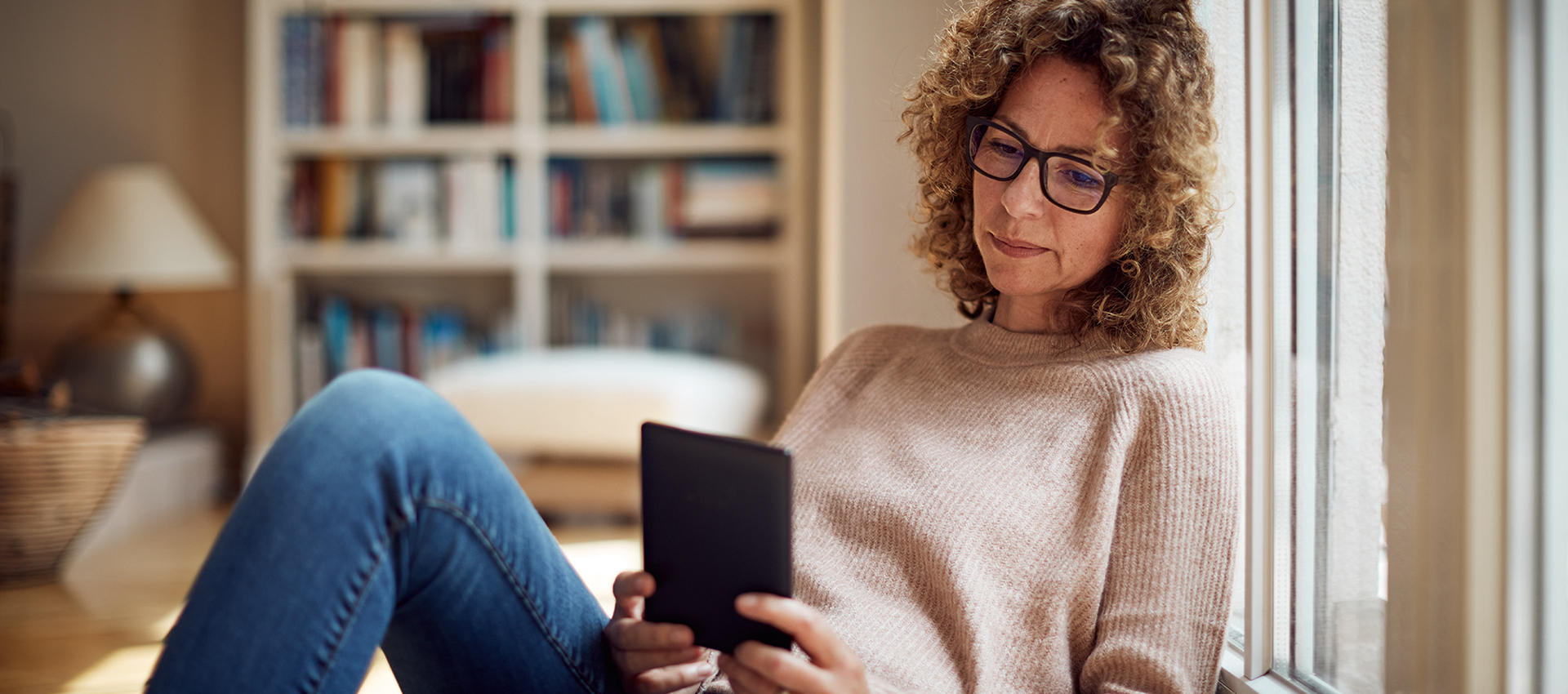 Frau mit lockigem Haar liest auf einem tolino-eReader
