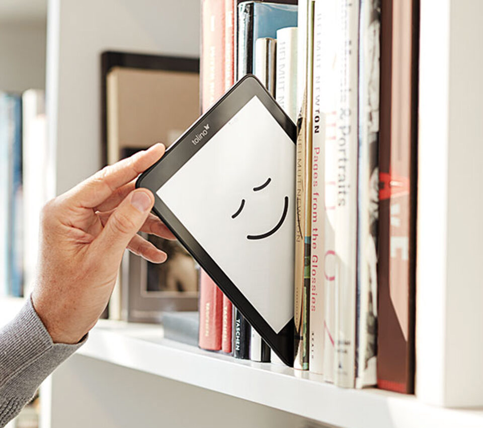 Männliche Hand zielt tolino-eReader aus Regal.
